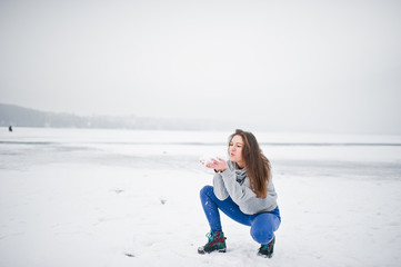 Funny girl wear on hoody sweater and jeans, at frozen lake in winter day.