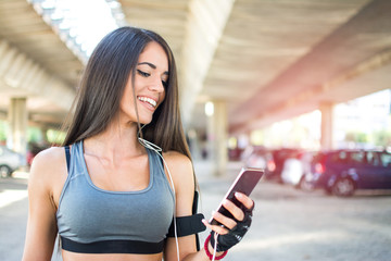 Sporty girl using mobile phone during exercise break outdoors