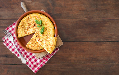 Traditional spanish omelette close up,  view from above. Spanish tortilla on a rustic wooden texture with a place for text.