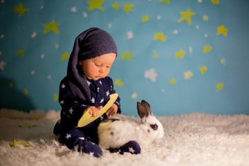 Little child, baby boy with cute white bunny and moon on a blue star and moon background