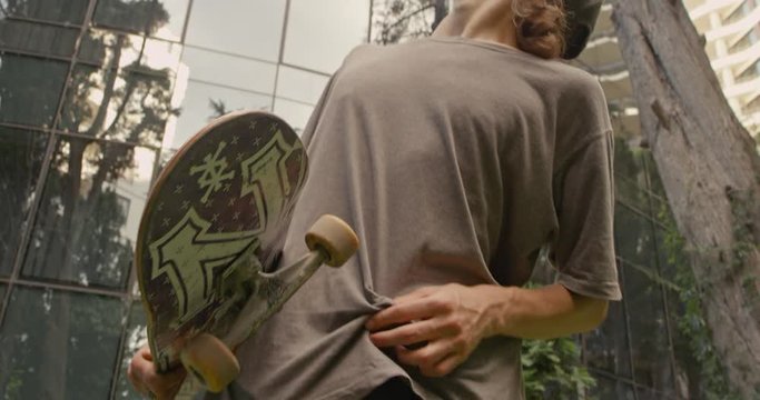 male carries longboard on shoulder and using smartphone slow motion