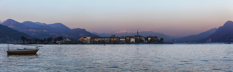 Obraz premium Reflections on the water by the lake at sunset. Fisherman Island, Lake Maggiore, Italy.