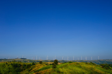 Windmills farm or Wind turbine power generators standing on green mountain against a blue sky, Located Khao Kho Phetchabun Province, Thailand