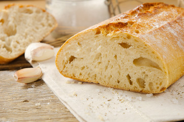 Ciabatta bread. Slices of ciabatta with garlic, salt on wooden table on linen cloth. Rustic style, italian. Close up
