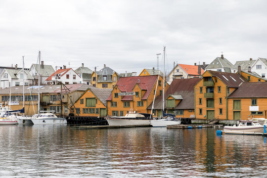 Haugesund, Norway - January 9, 2018: Old wooden houses on the island Risoy, boats and fishing industry buildings. Sild-eksport meaning Herring-export in norwegian.