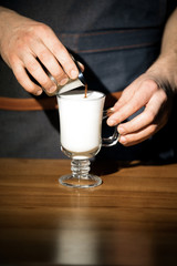 Hand on the barista, making a latte cafe, a cup of coffee with a beautiful latte