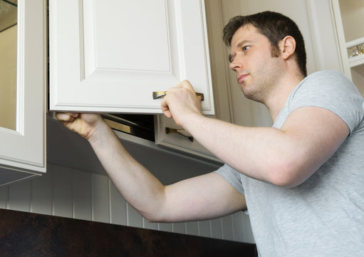 Professional handyman installing cabinet door in the kitchen.