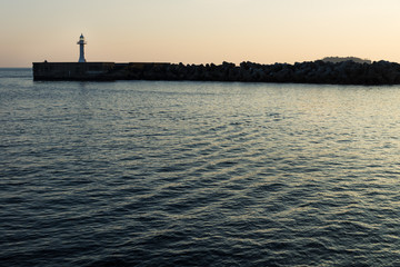 White lighthouse with yellow light at a seawall with wavebreakers in Seogwipo, Jeju Island, South Korea