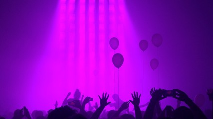 Ombres de foule mains levées et ballons à un concert (fond rose)