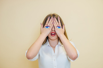 A young woman closes her eyes with her hands. Studio portrait of a model on a beige background....