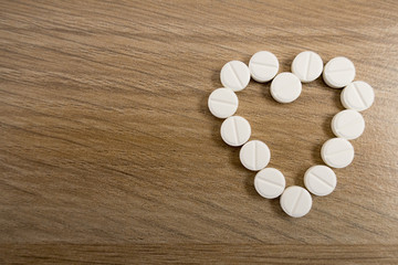 Fototapeta na wymiar Heart-shaped pills on a light wooden table close-up