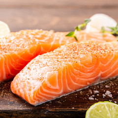Fresh raw salmon fillet with aromatic herbs, spices on old wooden background.