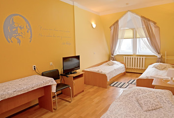The triple hotel room with a portrait of the Russian writer L.N. Tolstoy on a wall
