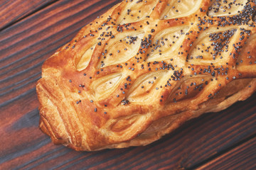 Baked bun with puff pastry, sprinkled with poppy seeds on a dark wooden background. Close-up. Food background.