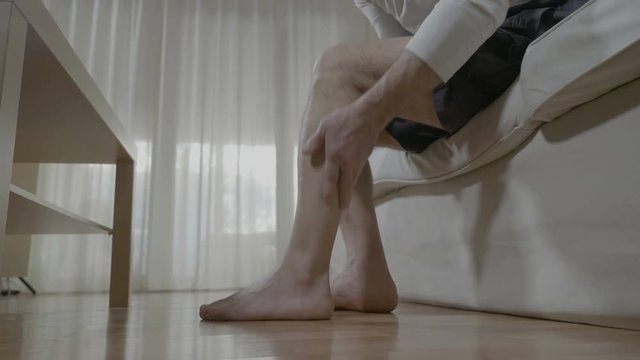 Senior man doing himself massage therapy on his tired legs relieve the pain and stress at home