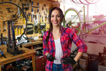 Fototapeta na wymiar Young woman working in a bicycle repair shop 