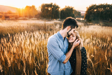 handsome guy with a beard in a blue denim shirt gentle hugs, hand holding and kissing a girl with...