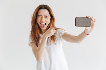 Naklejka premium Happy woman in casual clothes making selfie on smartphone