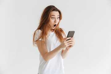 Fototapeta premium Shocked woman in casual clothes writing message on smartphone