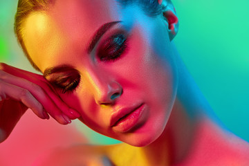 High Fashion model woman in colorful bright lights posing in studio