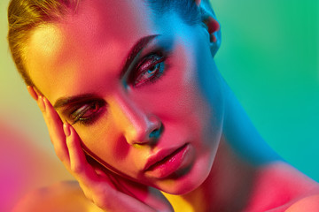 High Fashion model woman in colorful bright lights posing in studio