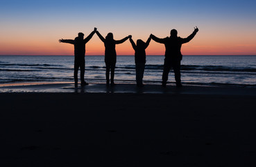 Fototapeta premium family silhouette on the beach after the sunset