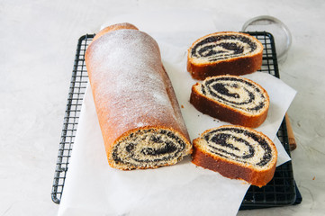 Traditional polish festive pastry - Makowiec- Poppy seed roll served on a wire rack. White stone background.