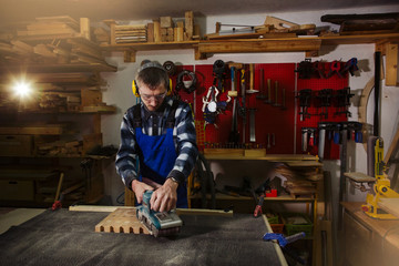 worker grinds  board in  woodworking workshop on an old workbench
