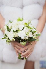 Obraz na płótnie Canvas Green white wedding bouquet in bride's hands dressed in fur coat outdoors. Wedding agency magazine concept.