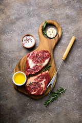 Raw meat with herbs and spices. Raw beef steak on cutting board with rosemary and ingredients. Top view