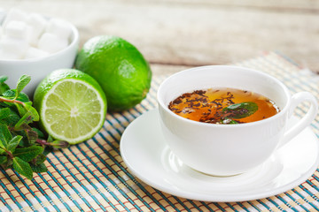 cup of black tea with mint leaves on a wooden table