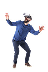 Excited young adult man bending and crouching having virtual reality glasses experience. Full body isolated on white background. 