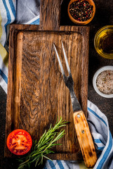 Old cutting board with Carving Fork, herb and spices on dark wooden background copy space top view