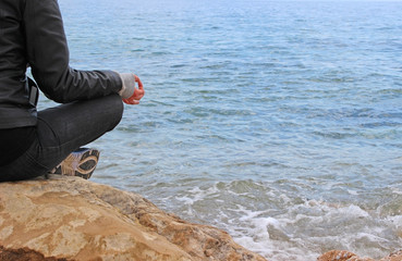 Woman in gyan mudra on the rocks. Sea is the background.