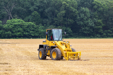 Yellow tractor sits idle in a golden field after harvest