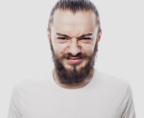 Portrait of a young bearded man frowning. Studio shot.
