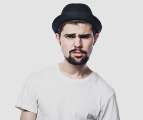 Portrait of bearded guy wearing black hat with unhappy expression on face