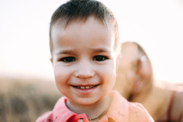 beautiful young mother in a long red dress with her little son walking on mountain sites on the sunset in summer, dry grass