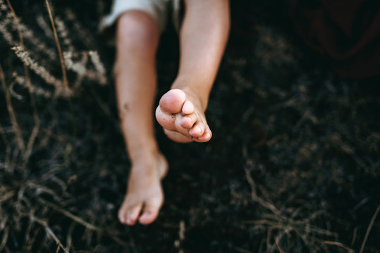  little son walking on mountain sites on the sunset in summer, dry grass. bare little feet in the grass