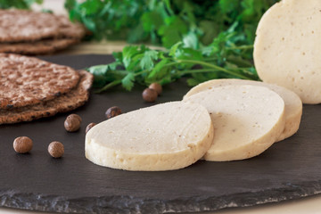 Dietary homemade chicken mortadella with spices on slate board. Protein rye multicereal flatbread. White background.