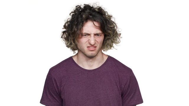 Portrait of caucasian guy sniffing and expressing disgust on his face due to bad smell, over white background. Concept of emotions
