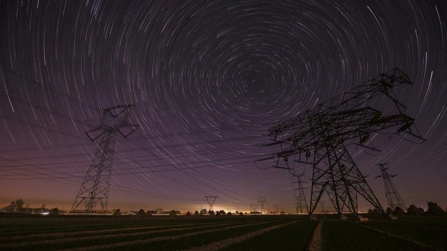 Night time lapse of high-voltage power lines on the background of the starry sky
