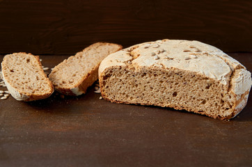 Homemade sliced appetizing fresh bread on the wooden background ready to eat. Just baked round bread on the brown table with free copy space. Side view