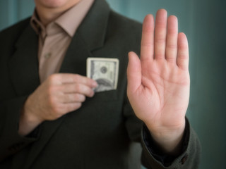 the man's hand shows a stop sign and the other hand hides the dollar bills in his jacket pocket.