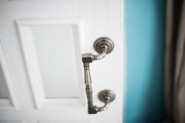 Door handle with silver color and white door in the room
