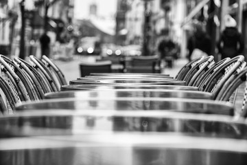 Street view of a Cafe terrace with empty tables and chairs. black and white photo.