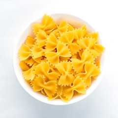farfalle macaroni pasta in white bowl on white isolated background in the center close-up with top.
