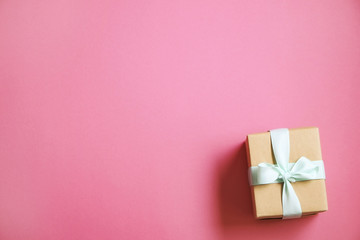 Single present wrapped in hand made craft paper gift wrap, tied w/ pastel satin bow. Simple giftbox, brown wrapping, giftwrap, blue ribbon. Holiday concept. Close up, background, copy space, top view.
