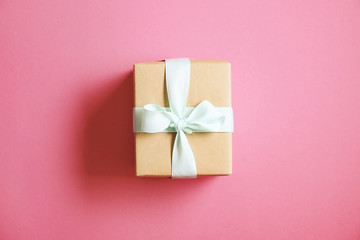 Single present wrapped in hand made craft paper gift wrap, tied w/ pastel satin bow. Simple giftbox, brown wrapping, giftwrap, blue ribbon. Holiday concept. Close up, background, copy space, top view.