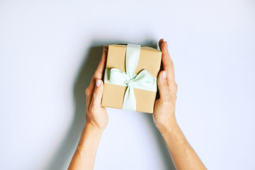 Young woman holding bunch of presents wrapped in hand made blank craft paper gift wrap, satin bow. Female hands, simple giftbox, wrapping, giftwrap, silk ribbon. Blue background, close up, copy space.